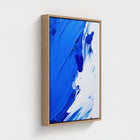 Abstract art print with blue and white colors in a wooden frame on a light gray background