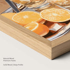 Artwork of oranges and drinks glasses on a tray in a natural wood frame.