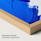 Blue abstract painting with a natural wood frame on a plain background