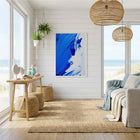 Modern living room with abstract blue art print, natural light, and coastal decor.