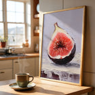 Framed art print of a sliced fig on a kitchen counter with a steaming cup of coffee.