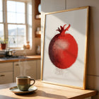 Framed art print of a red pomegranate on a kitchen counter with a steaming cup of coffee.