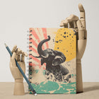 Notebook with elephant design held by wooden hands on a beige background