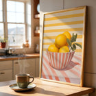 Framed art print of a bowl of lemons on a kitchen counter with a steaming cup of coffee.