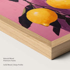Artwork of lemons on a pink background within a natural wood frame.