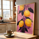 Framed art print of lemons on a pink background in a kitchen setting with a steaming cup of coffee.