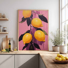 Framed art print of lemons on a pink background in a kitchen setting.
